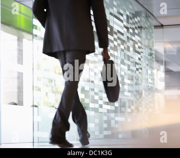 Imprenditore con valigetta a piedi nella lobby Foto Stock