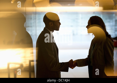 Imprenditore e imprenditrice handshaking nella lobby Foto Stock