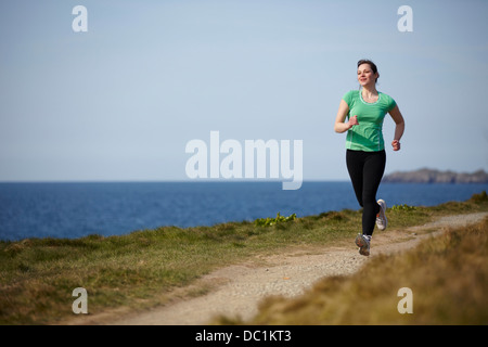 Giovane donna che corre lungo il percorso costiero Foto Stock