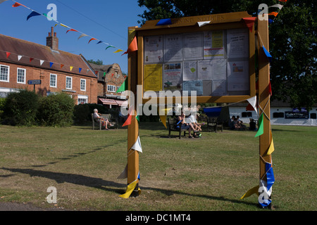 E Pennents bunting sul villaggio verde a Horning, un villaggio turistico su Norfolk Broads. Horning è un antico villaggio e parrocchia nella contea inglese di Norfolk. Horning significa 'folk che vivono sulla terra alta tra i fiumi". La sua storia risale al 1020 quando il maniero fu data dal re canuto alla neonata Abbazia di San Benet a Hulme. Horning è pittoresco e descritta come la più bella villaggio sul broads. Foto Stock