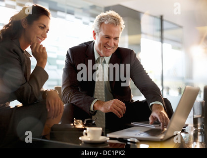 Imprenditore sorridente e imprenditrice utilizzando portatile nella hall Foto Stock