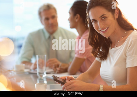 Ritratto di imprenditrice sorridente con un telefono cellulare in riunione Foto Stock