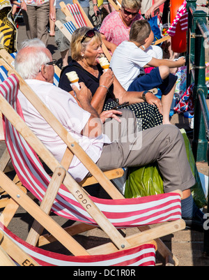 Mangiare gelato su sedie a sdraio, Sidmouth lungomare, Devon, Inghilterra Foto Stock