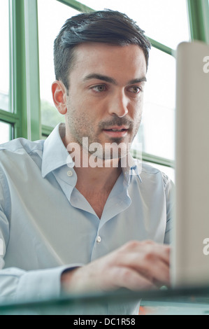 Chiusura del giovane maschio lavoratore di ufficio con computer portatile Foto Stock