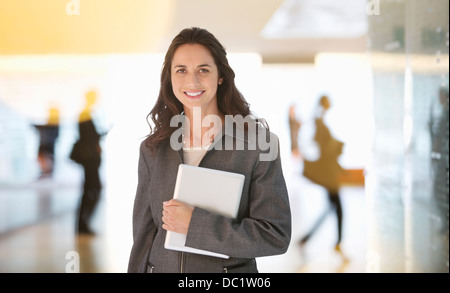 Ritratto di sorridere imprenditrice azienda digitale compressa nella lobby Foto Stock