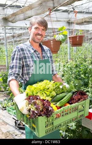Ritratto di agricoltore biologico portando un vassoio di prodotti freschi Foto Stock