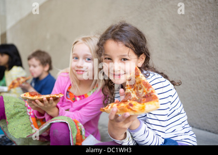 Piccolo gruppo di bambini mangiare la pizza all'aperto Foto Stock