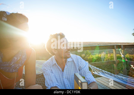 Coppia giovane seduti sul balcone soleggiato e sorridente Foto Stock