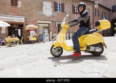 Uomo su scooter nella piazza del villaggio Foto Stock