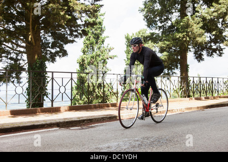 Ciclista riding down road in Umbria, Italia Foto Stock