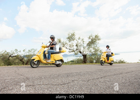 Giovane su scooter riding fino strada rurale Foto Stock