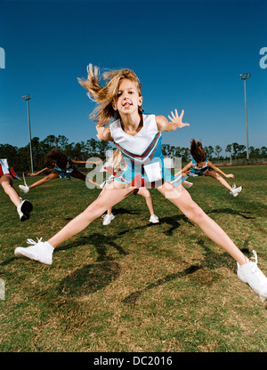 Cheerleaders di eseguire la routine di danza sul campo sportivo Foto Stock