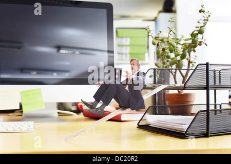 Imprenditore maturo lo scorrimento verso il basso dominatore sulla scrivania di grandi dimensioni Foto Stock