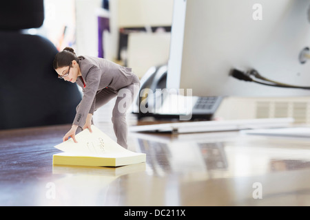 Imprenditrice utilizzando grandi etichetta adesiva sulla scrivania di grandi dimensioni Foto Stock
