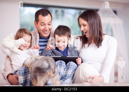 I genitori, due bambini e cane guardando a tavoletta digitale Foto Stock