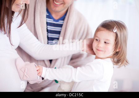 Giovane figlia holding baby scarpine sulle madri bump Foto Stock