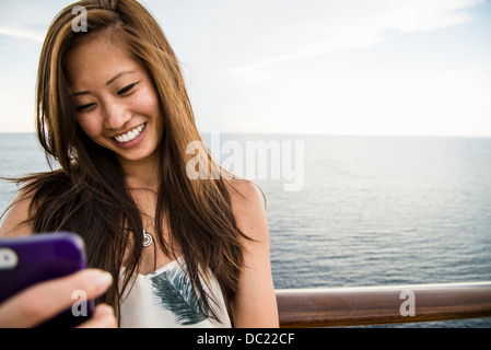 Giovane donna utilizzando il telefono cellulare in mare Foto Stock