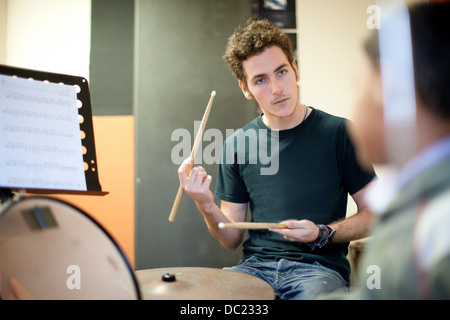 Giovane maschio ragazzo di insegnamento come suonare drum kit Foto Stock