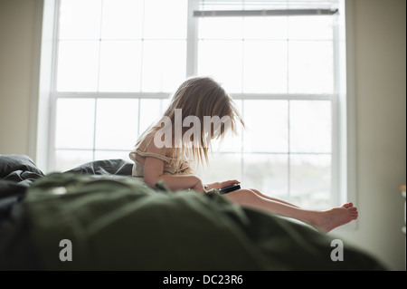 Ragazza seduta sul letto utilizza lo smartphone Foto Stock