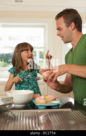 Giovane ragazza glassa mettendo il fratello più anziano del naso Foto Stock