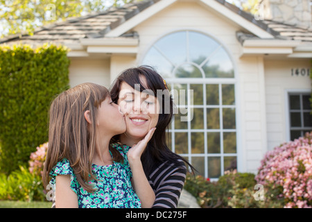 Ritratto della figlia di madre baciare sulla guancia in giardino Foto Stock