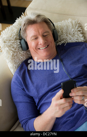 Uomo maturo che indossano le cuffie, sorridente Foto Stock