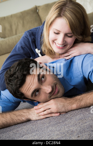 Coppia giovane sdraiato sul pavimento, donna sulla parte superiore dell'uomo Foto Stock