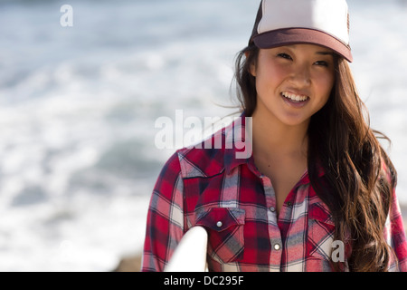 Giovane donna indossa berretto da baseball con tavola da surf Foto Stock