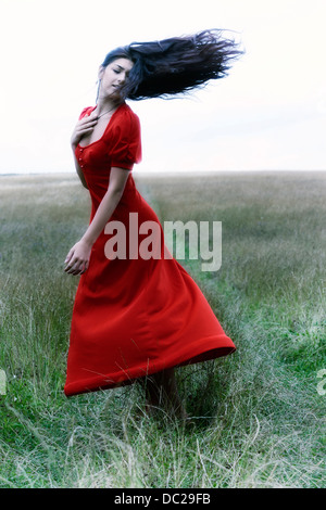 Una ragazza in un abito rosso sta ballando su un campo Foto Stock