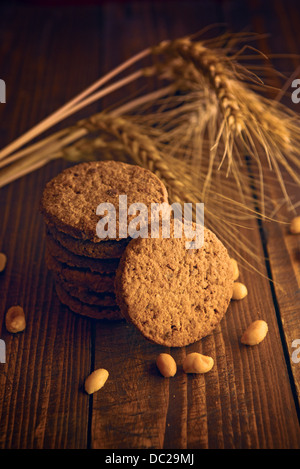 I biscotti al cioccolato. Deliziosi e freschi cookies sul tavolo di legno con alcune spighe di grano e di arachidi. Foto Stock