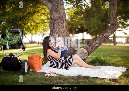 Madre seduta sulla coperta picnic con la nostra bambina Foto Stock