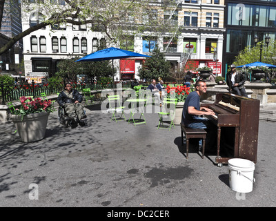 Felice giovane uomo gioca battere un pianoforte per audience di tipo sparse tra cui l uomo in sedia a rotelle sulla bella e soleggiata giornata di primavera Union Square Foto Stock