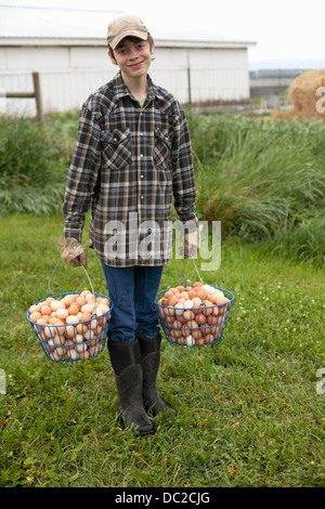 Ragazzo che trasportano due cesti di uova Foto Stock