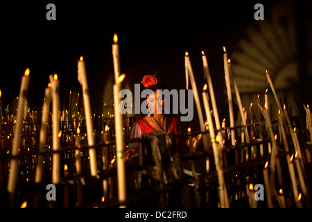 Una donna accende una candela nella camera votiva del santuario della Vergine del Rocio in Andalusia, Spagna. Foto Stock