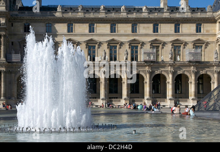 Una fontana in primo piano di una parte dell'Ala Richelieu, Palazzo del Louvre, Parigi, Francia Foto Stock