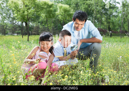 La famiglia felice osservando le piante con ingrandimento di-bicchieri Foto Stock