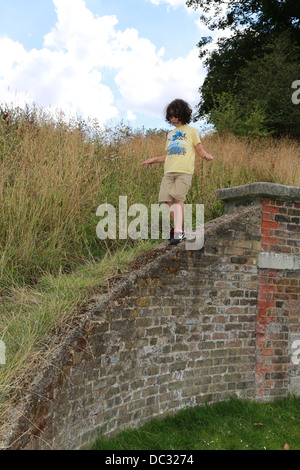 Ragazzo giovane a camminare su una parete Foto Stock