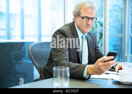 Imprenditore per la messaggistica di testo con il cellulare in sala conferenze Foto Stock