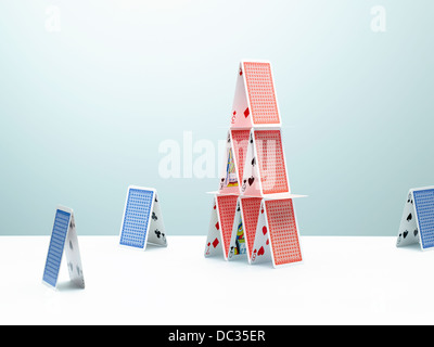 Contrastanti di piccole case di carte che circonda questa grande casa di carte Foto Stock