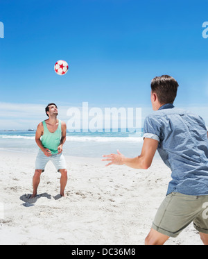 L'uomo voce pallone da calcio sulla spiaggia Foto Stock