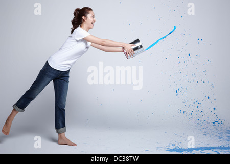 Una signora di gettare una dipinge dal secchio di vernice Foto Stock