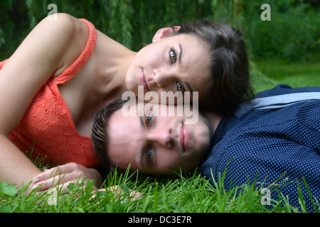 Coppia giovane posa sull'erba con la donna in appoggio la sua testa a Le Mans in un ambiente da giardino Foto Stock