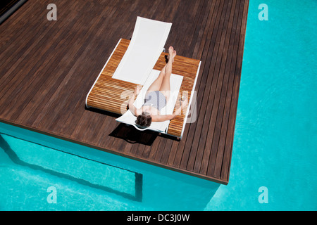 La donna a prendere il sole a bordo piscina Foto Stock