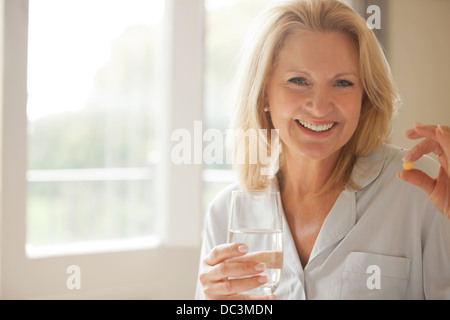 Ritratto di donna sorridente holding pillola e bicchiere di acqua Foto Stock