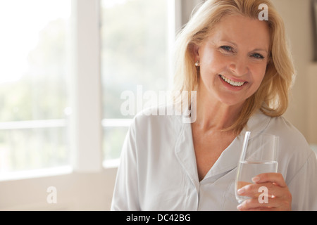 Ritratto di donna sorridente di bere un bicchiere di acqua Foto Stock