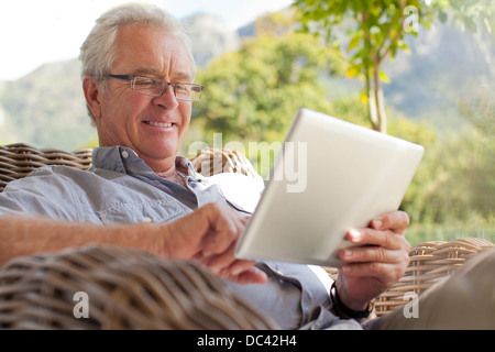 Sorridente uomo senior con tavoletta digitale sul patio Foto Stock