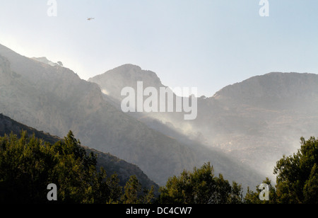 Il fumo vola sopra Estellencs montagne dell'isola di Mallorca dopo una massiccia diffusione di un incendio circa 2300 ettari. Foto Stock