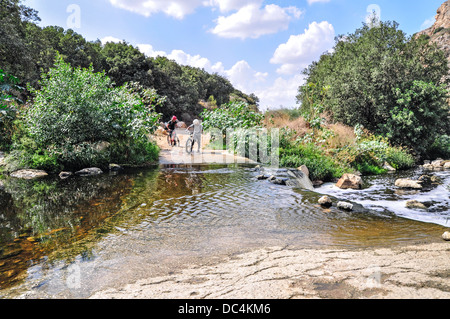 Due ciclisti prepairing per attraversare il fiume con la mountain bike Foto Stock