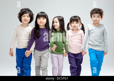 Bambini passeggiate in linea mano nella mano Foto Stock