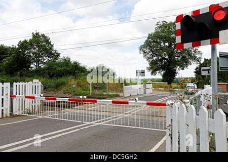 Un passaggio a livello ferroviario nel Regno Unito campagna, con barriere chiuse e luci lampeggianti Foto Stock